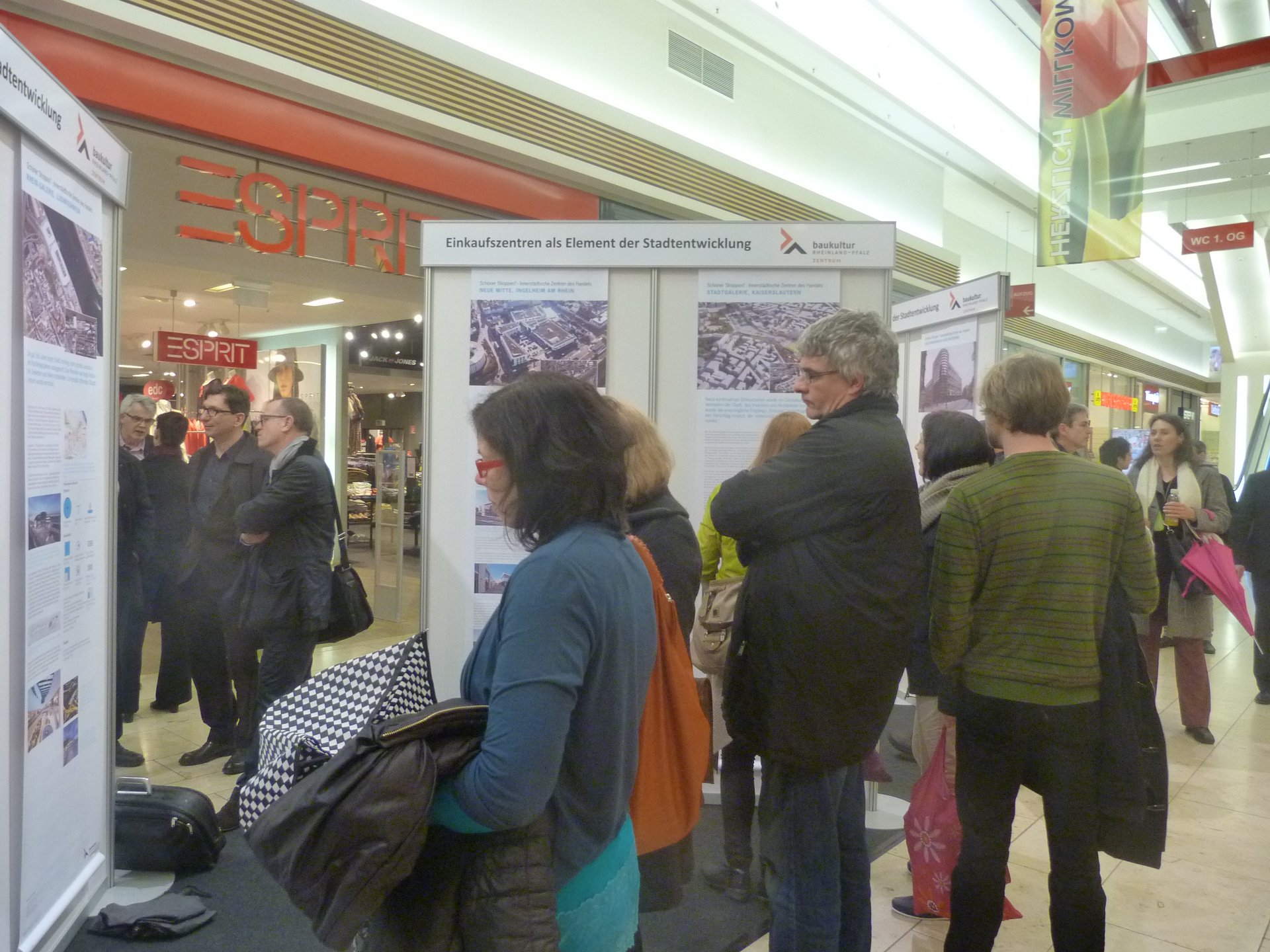 Menschen in einer Einkaufspassage betrachten die Ausstellung „Schöner Shoppen“. (Foto: Birgit Brüggen)